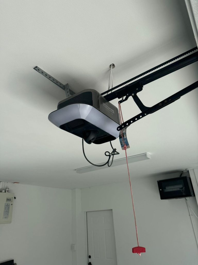 General Repair & Installition | Garage Door Repair Fort Myers 7 Garage door opener mounted on ceiling with safety release cord, highlighting modern garage door technology relevant to security and functionality.
